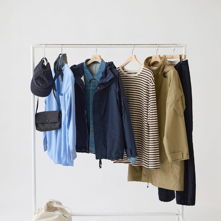 Clothing rack with various jackets, shirts, and a bag on a white background